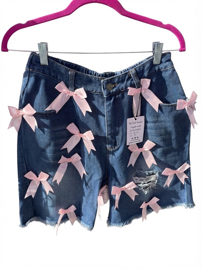 Distressed denim Bermuda shorts with pink bow accents ￼ Hover Image